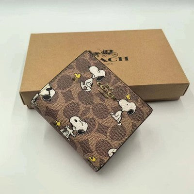 Shop the Coach x Peanuts snap wallet featuring signature coated canvas, Snoopy print, card slots, ID window, bill compartment and exterior zip coin pocket.