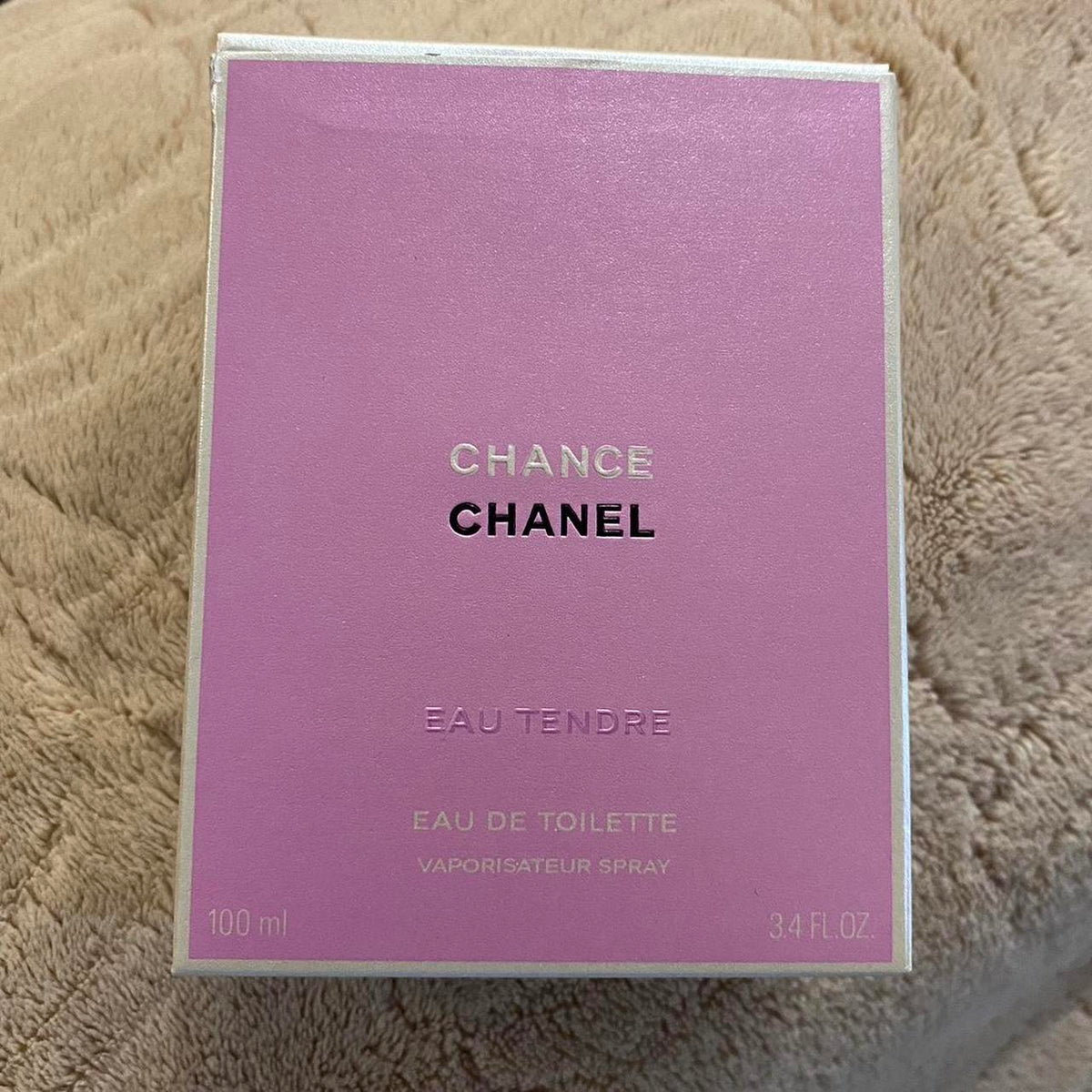 Chanel Change Eau Tendre Eau de Toilette spray box in a light purple/lavender color, resting on a beige textured blanket background.